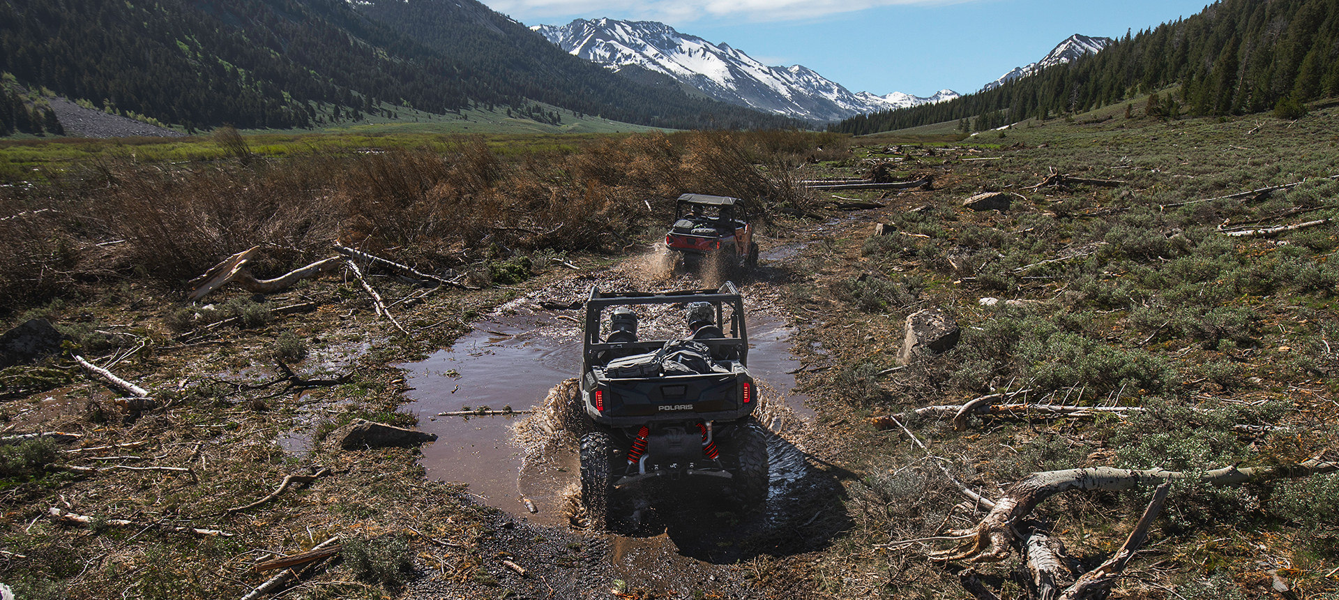 Two General vehicles riding through a muddy trail