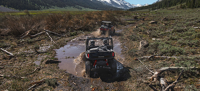 Two General vehicles riding through a muddy trail