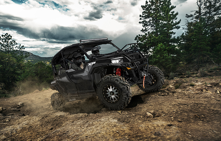 General XP 1000 vehicle riding uphill on a trail in the woods