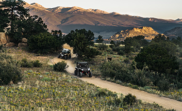 Two General XP 1000 vehicles riding on a trail in the woods