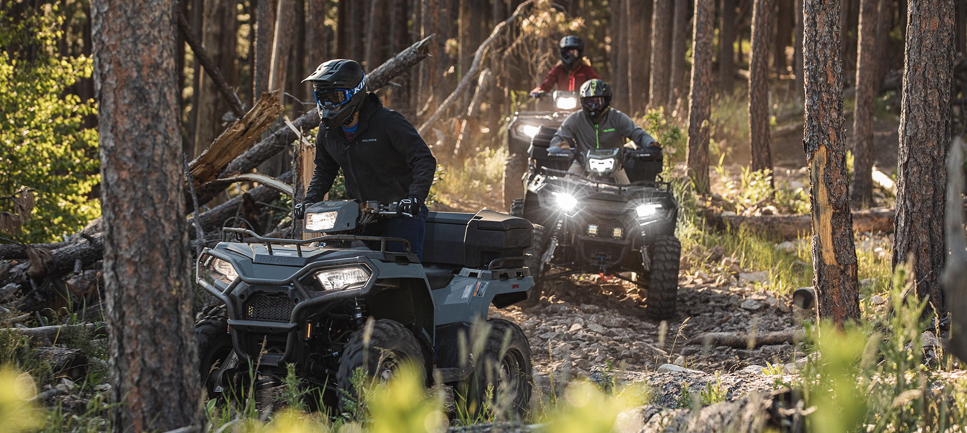 A group of Sportsman 450 riders in the woods