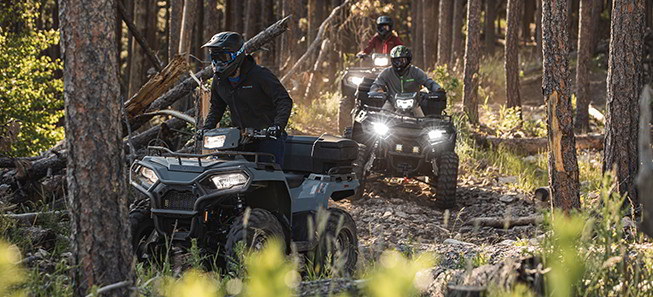 A group of Sportsman 450 riders in the woods