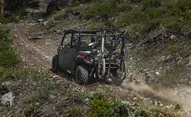 Polaris General 4 1000 side by side hauling 2 bikes up a rocky hill