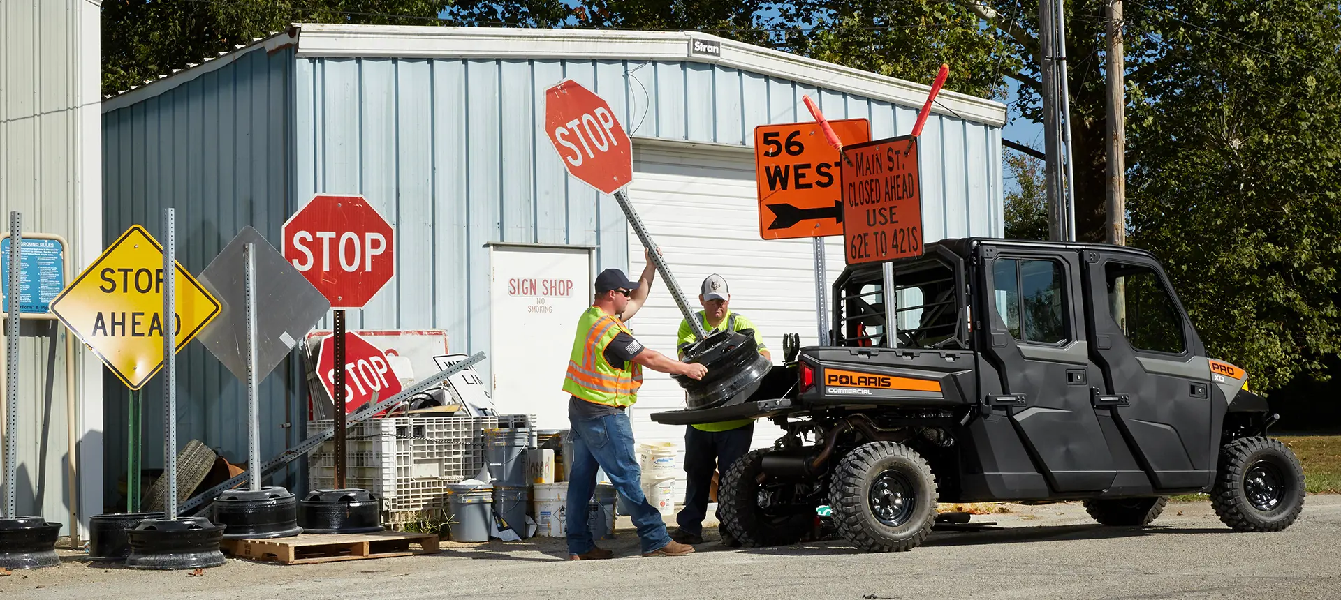 2 city employees loading signs into the cargo box of a pro xd full-size diesel crew work UTV