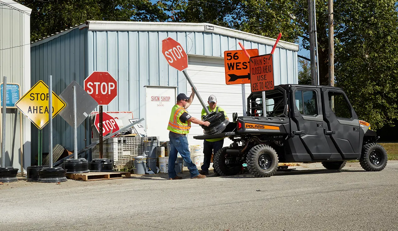 2 city employees loading signs into the cargo box of a pro xd full-size diesel crew work UTV
