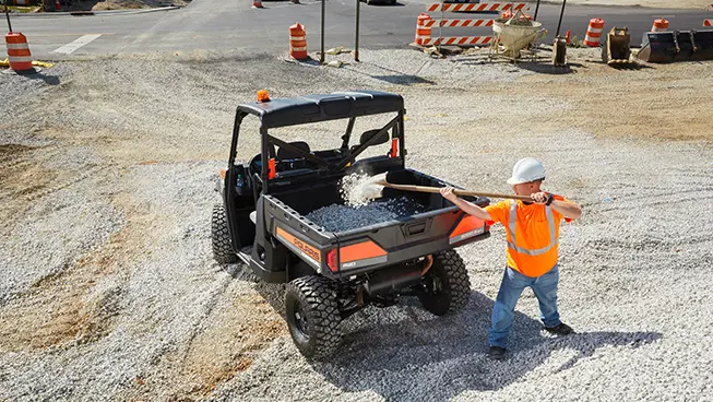 construction worker loading gravel into the cargo box of a pro xd full-size diesel work UTV