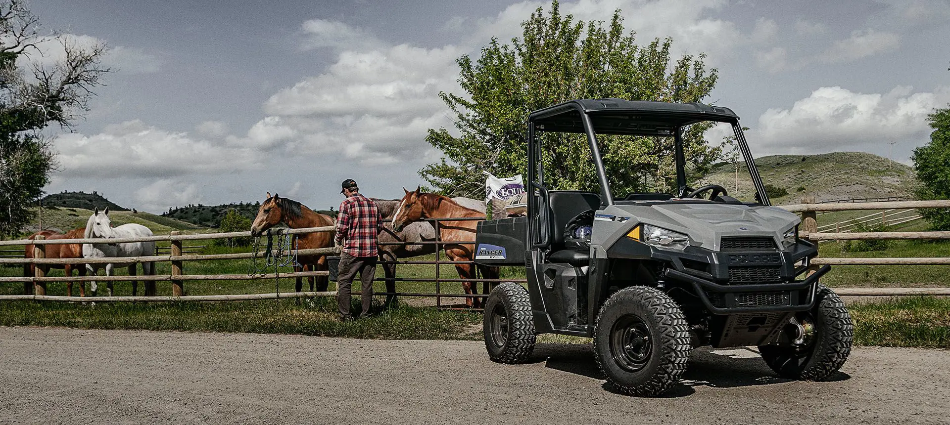 man feeding his horses with feed from the cargo box of his polaris ranger ev