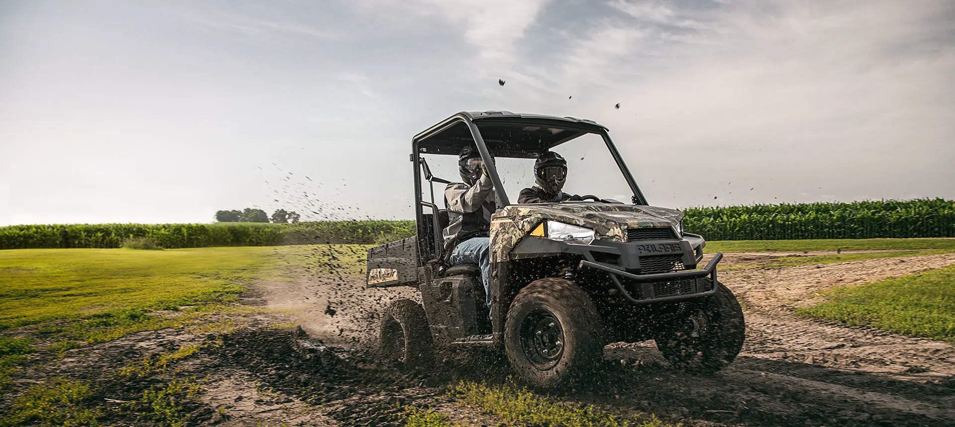 2 riders ripping through the mud in a polaris ranger ev electric utv