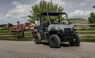 man feeding his horses with feed from the cargo box of his polaris ranger ev