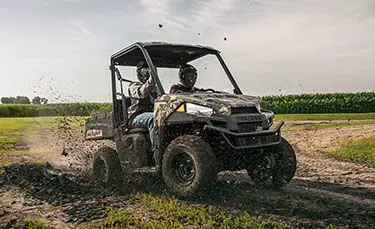 2 riders ripping through the mud in a polaris ranger ev electric utv