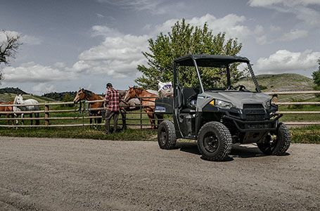 man feeding his horses with feed from the cargo box of his polaris ranger ev