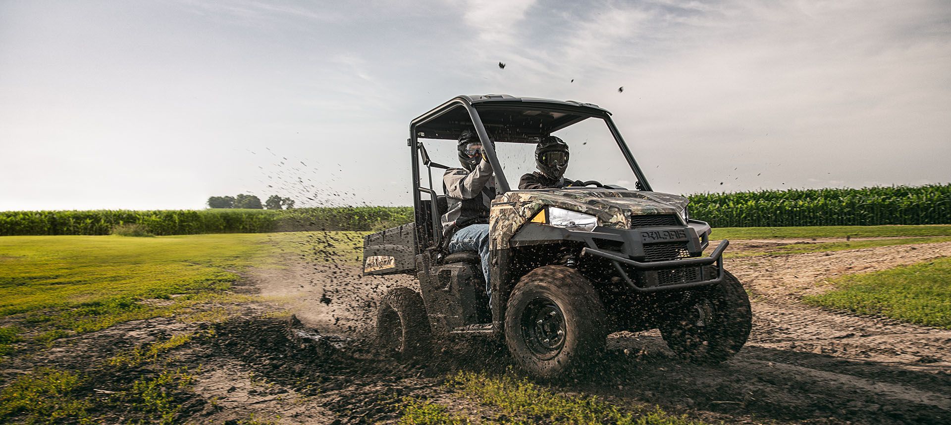 2 passengers in a ranger ev having fun driving through muddy terrain