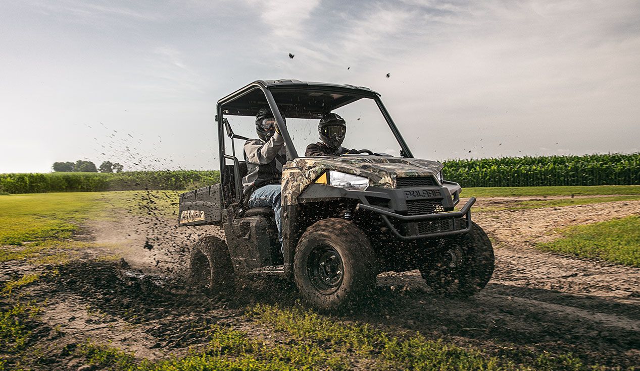 2 passengers in a ranger ev having fun driving through muddy terrain