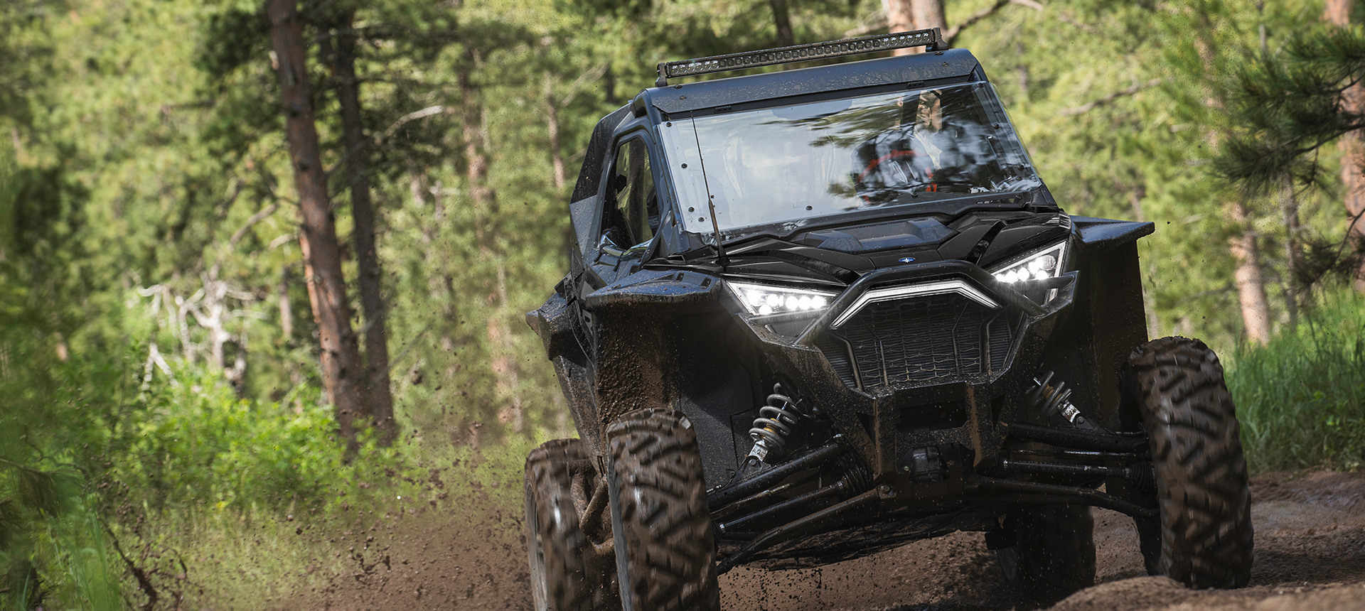 Front view of a RZR Pro XP riding on a muddy trail