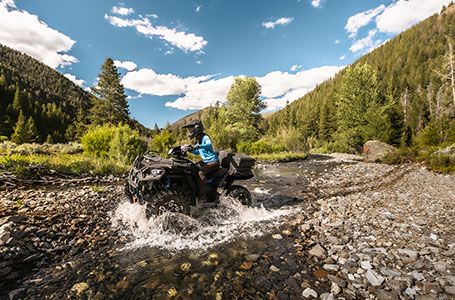 Sportsman 570 traversing a stream.