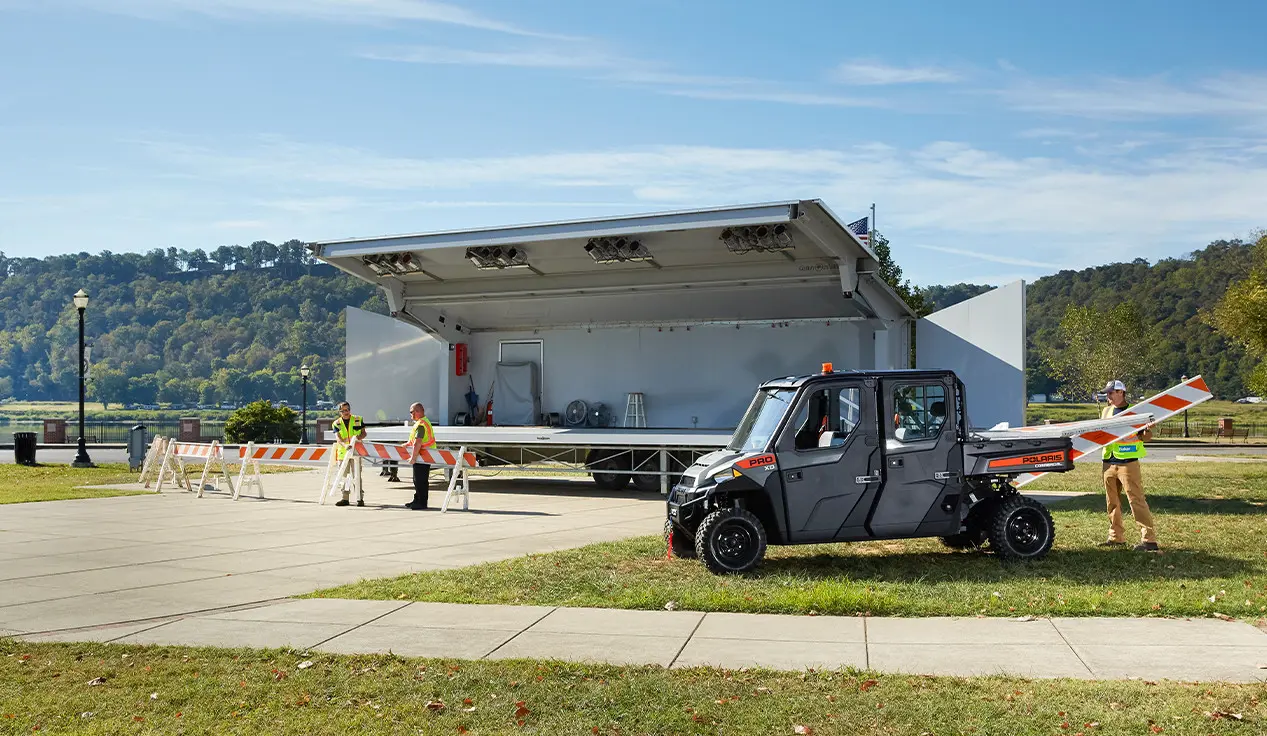 People loading barriers into the cargo box of a Polaris Pro XD UTV used for grounds and facility operations.