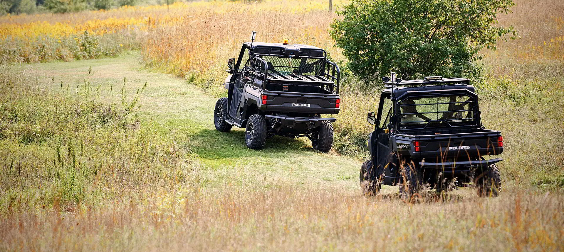 2 polaris rangers with terrain and wildlife management packages driving on a trail