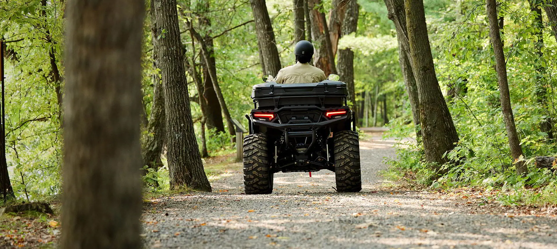 person driving a polaris sportsman atv with a terrain and wildlife management package on a dirt trail