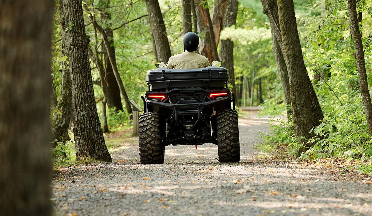 person driving a polaris sportsman atv with a terrain and wildlife management package on a dirt trail