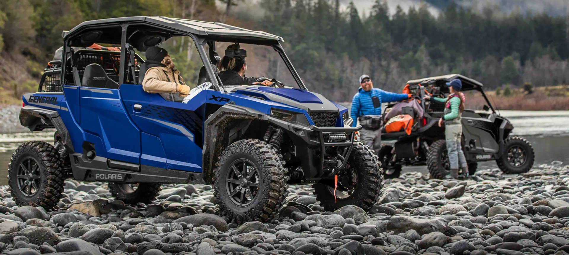 people hanging out in and around their general xp 4 1000 side by sides near a river