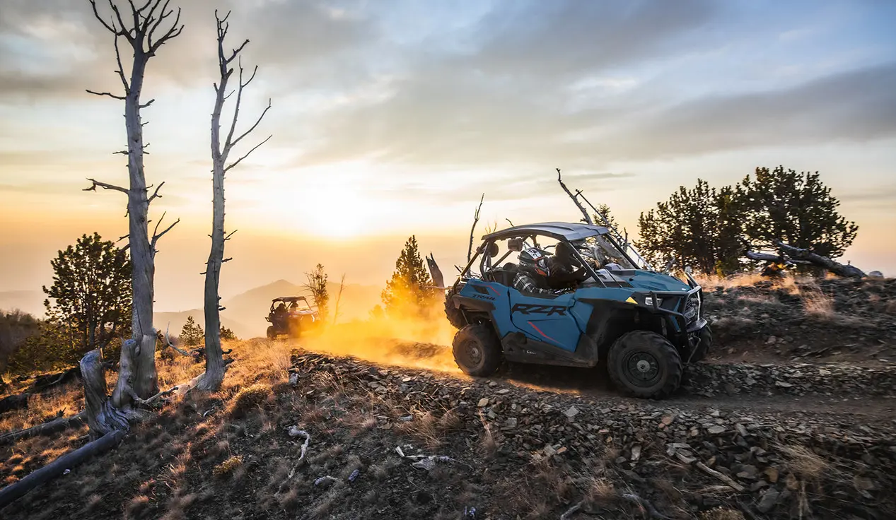 side view of a rzr trail side by side on a trail at dusk