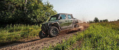 Polaris XPEDITION ADV riding through mud on an off-road trail.