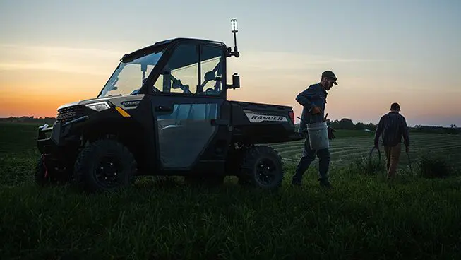 2 farmers grabbing gear to fix a fence from the cargo box of their Polaris RANGER 1000 UTV.