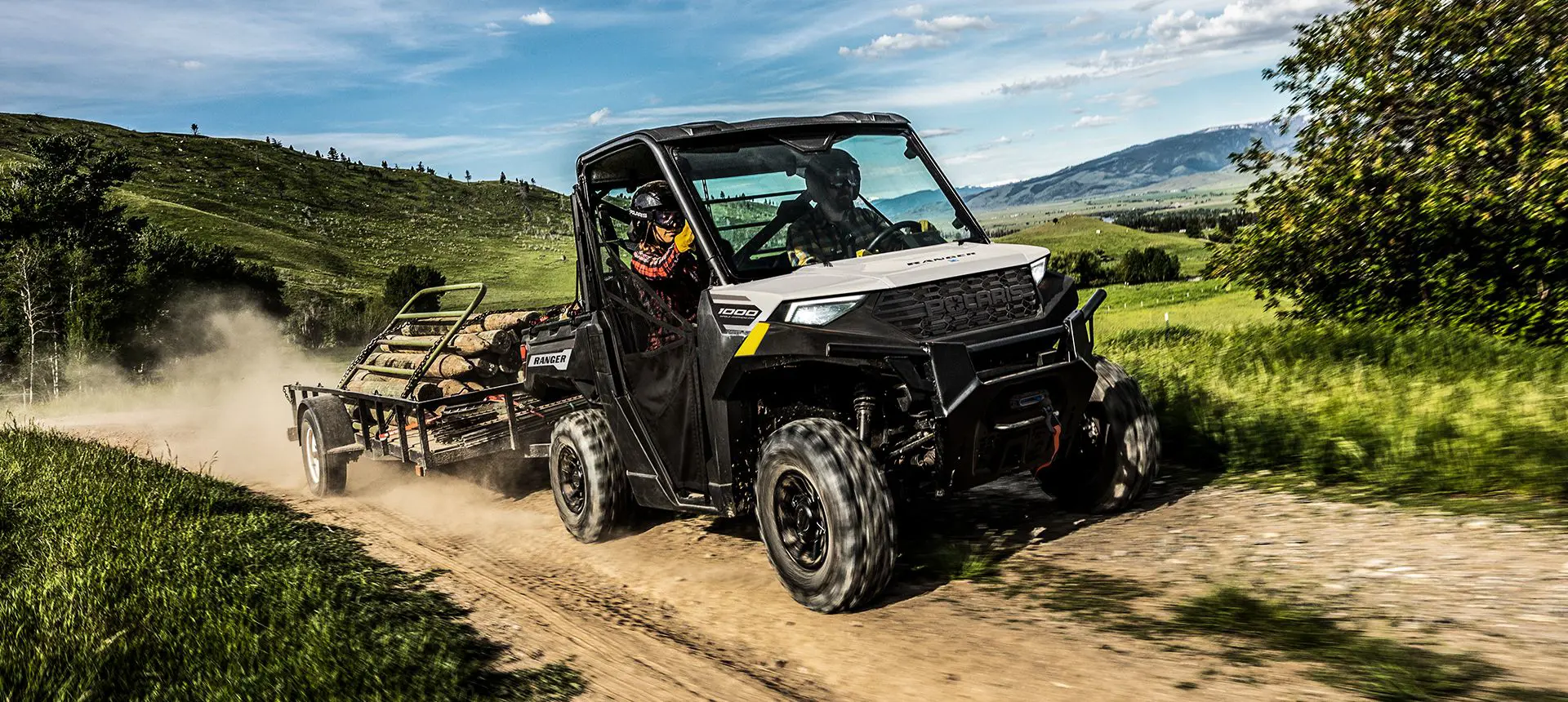 A Polaris RANGER 1000 UTV pulling a trailer loaded with fence posts.