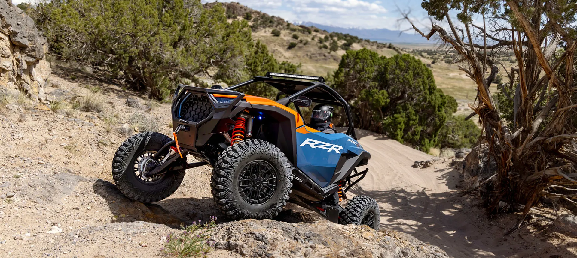 Polaris RZR Pro S side-by-side climbing over rocky terrain in the desert.