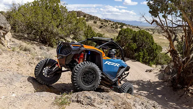 Polaris RZR Pro S side-by-side climbing over rocky terrain in the desert.