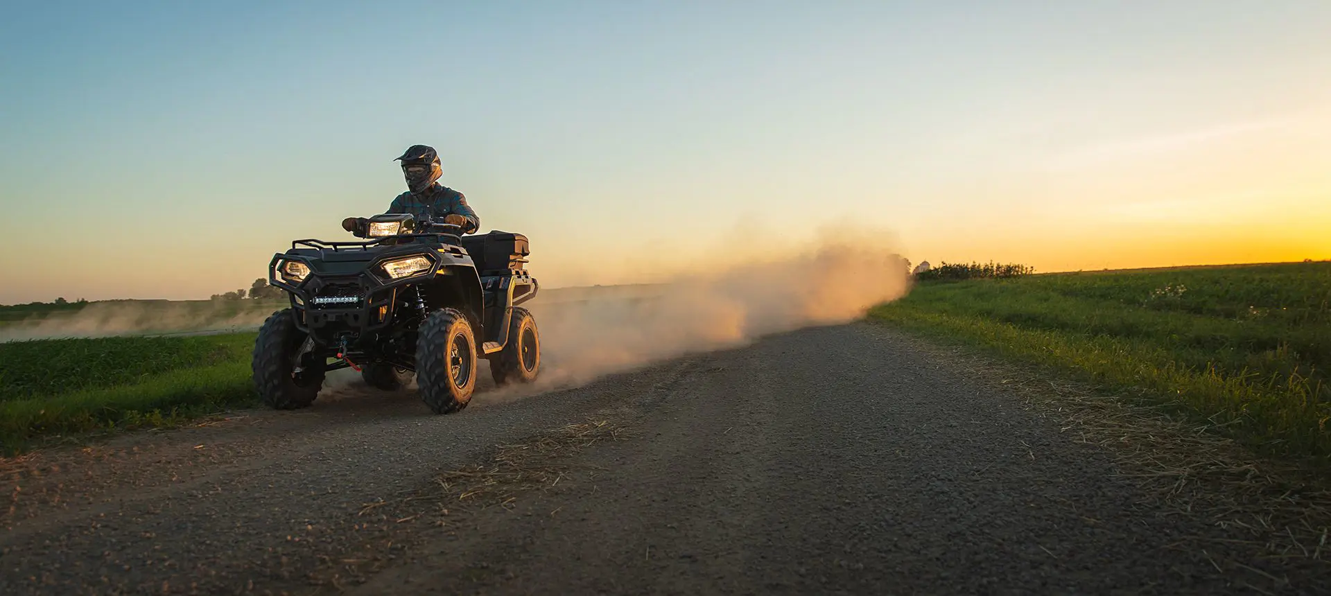 Polaris Sportsman 450 ATV driving down a dirt road.