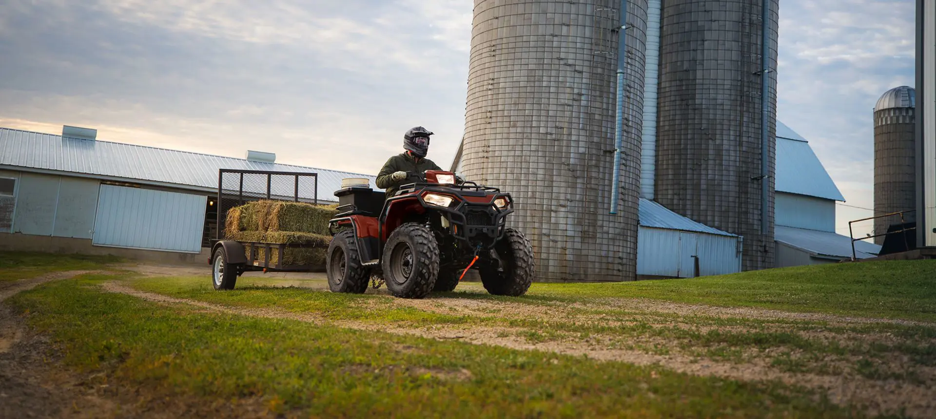 Polaris Sportsman 450 ATV pulling a trailer full of square bales.