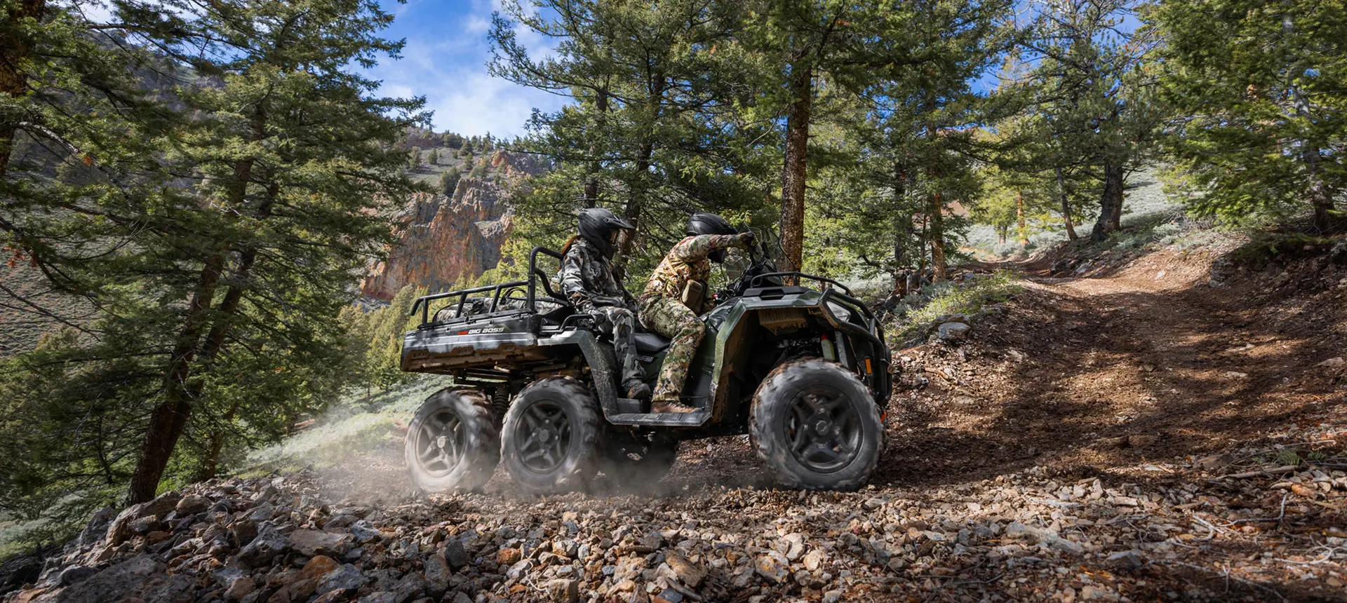 Side profile of a two people riding a trail on a Polaris Sportsman 6x6 570 ATV.