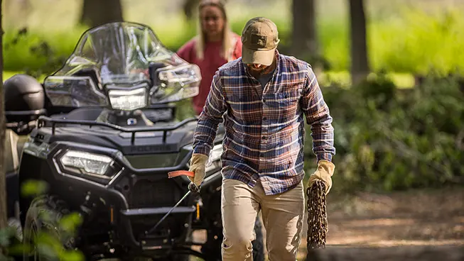 Man using the winch from the front-end of his Polaris Sportsman 6x6 570 ATV.