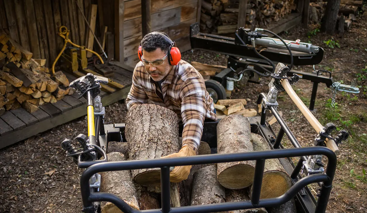 Man unloading wood from the cargo box of his Polaris Sportsman 6x6 570 ATV.