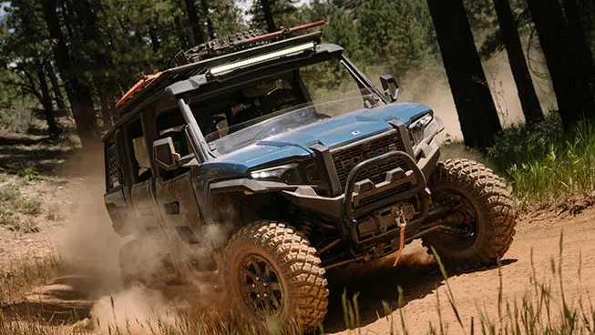 Front end close up of a Polaris XPEDITION ADV 5 side-by-side on a dusty trail.