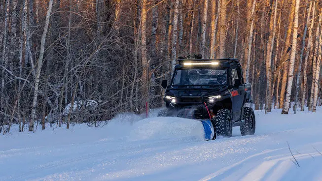 Person plowing snow with a Polaris XPEDITION XP side-by-side with snowplow accessory.