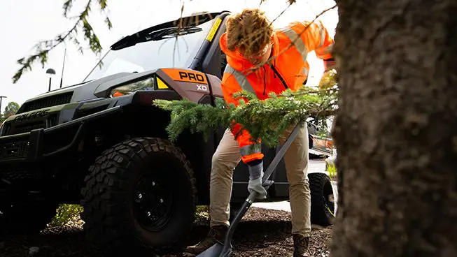 Person shoveling dirt near their Polaris Pro XD Full-Size work UTV.