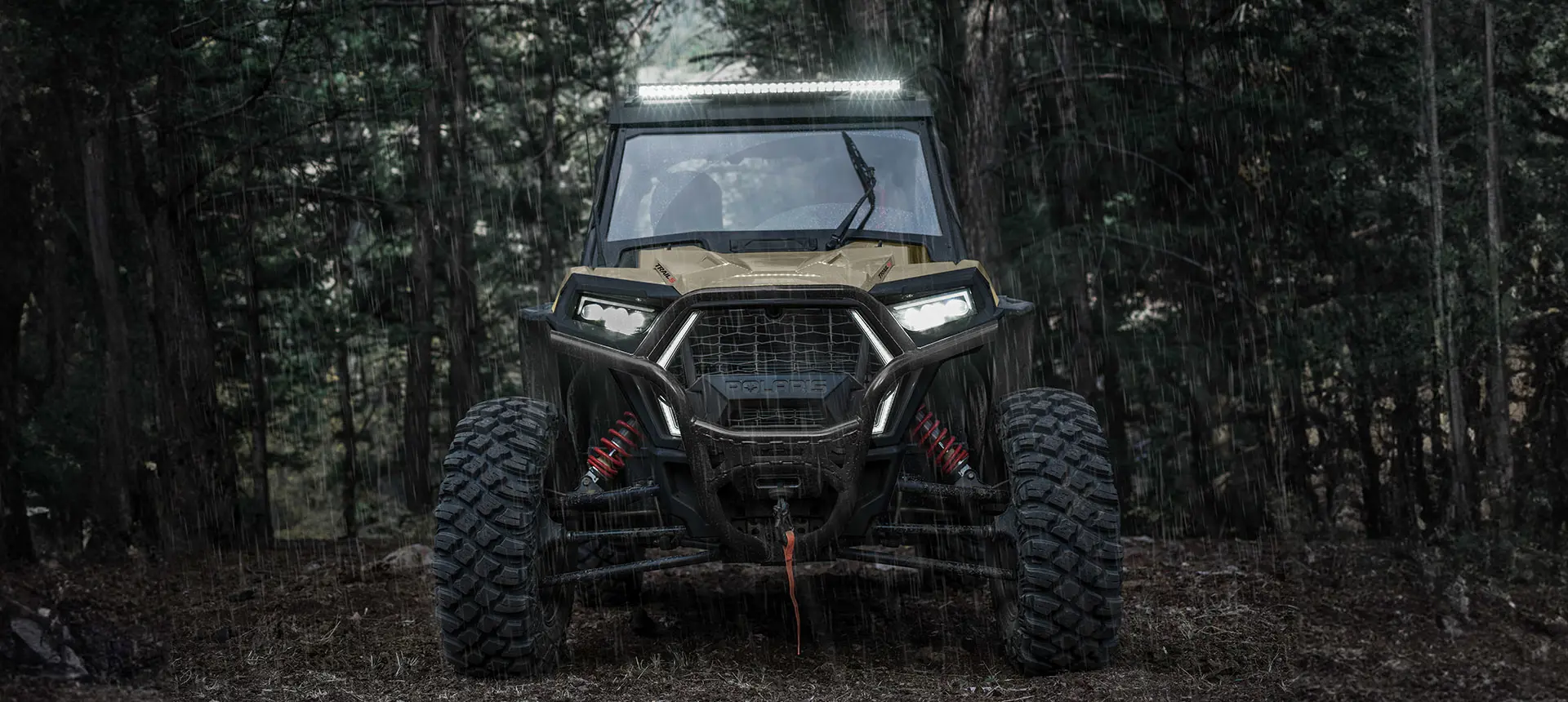 Front end view of a Polaris RZR Trail side-by-side with lights on.