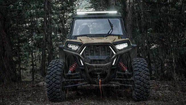 Front end view of a Polaris RZR Trail side-by-side with lights on.