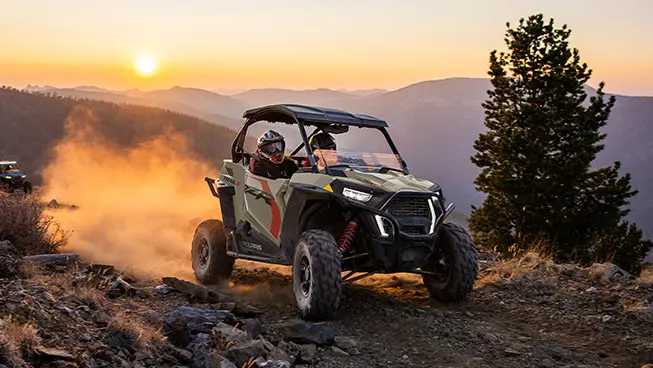 Polaris RZR Trail side-by-side driving at sunrise.