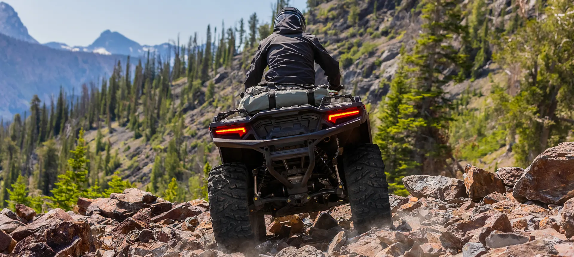 Rearview of a Polaris Sportsman 850 ATV driving over rocky terrain.
