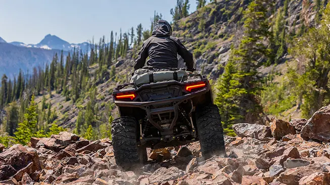 Rearview of a Polaris Sportsman 850 ATV driving over rocky terrain.
