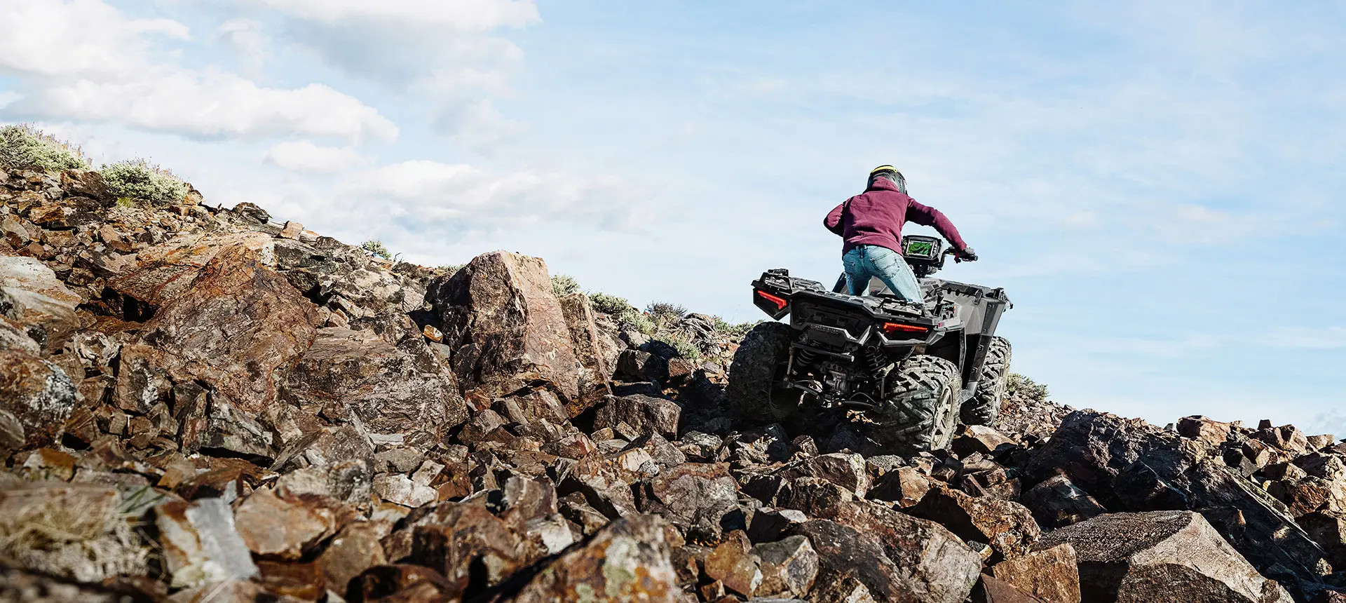 Person climbing rocky terrain with a Polaris Sportsman XP 1000 ATV.