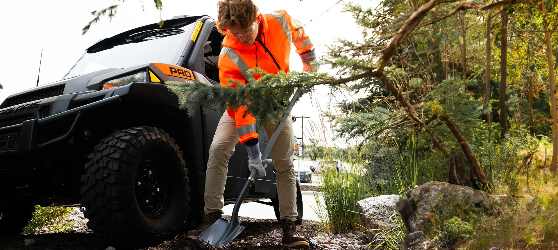 Person digging a hold near their Polaris Pro XD UTV for grounds and facility operations.