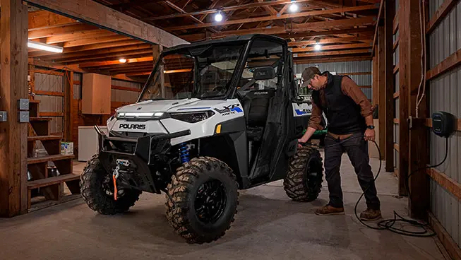 Person charging up a Polaris RANGER Kinetic UTV they use for grounds and facility operations.