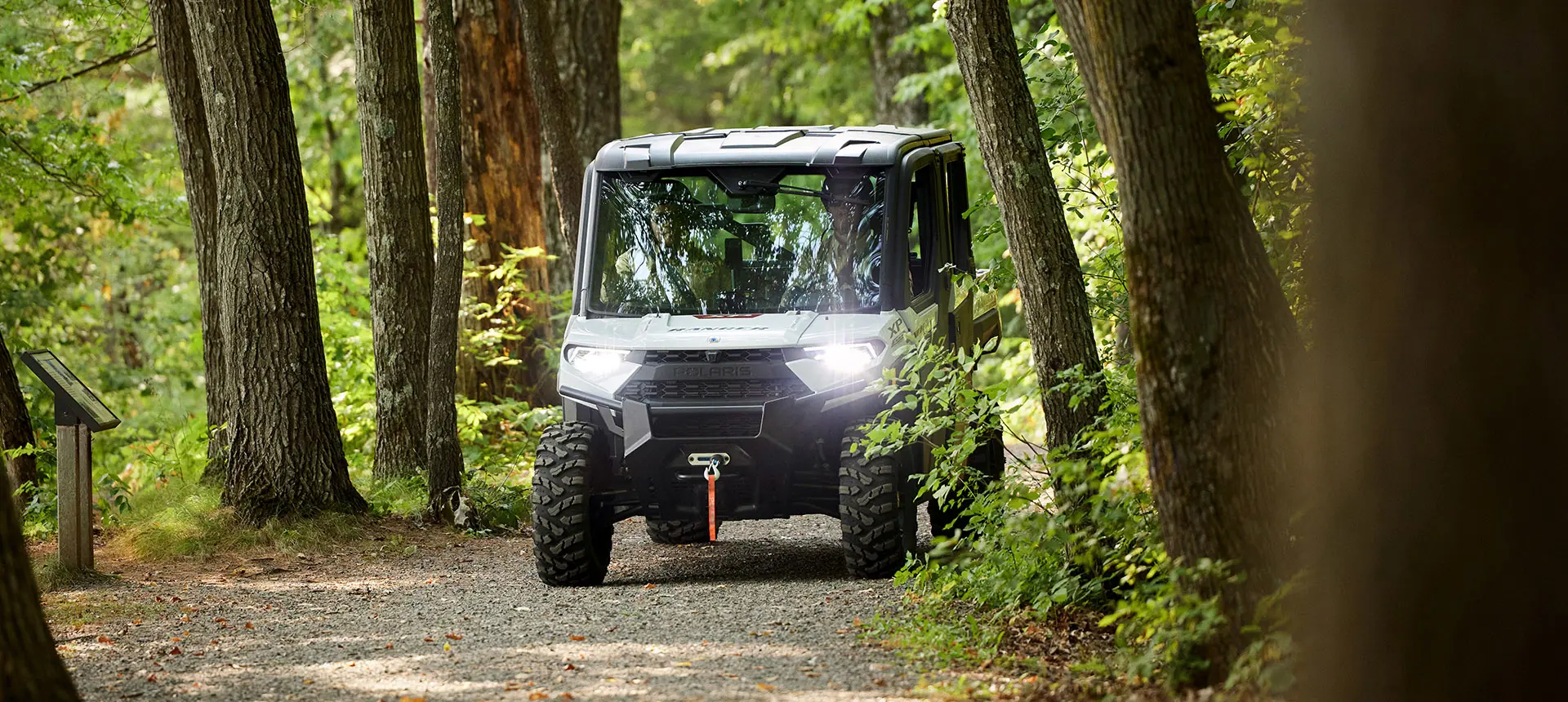 Two employees driving a Polaris RANGER UTV used for grounds and facility operations.