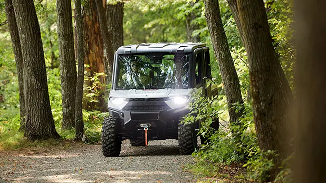 Two employees driving a Polaris RANGER UTV used for grounds and facility operations.