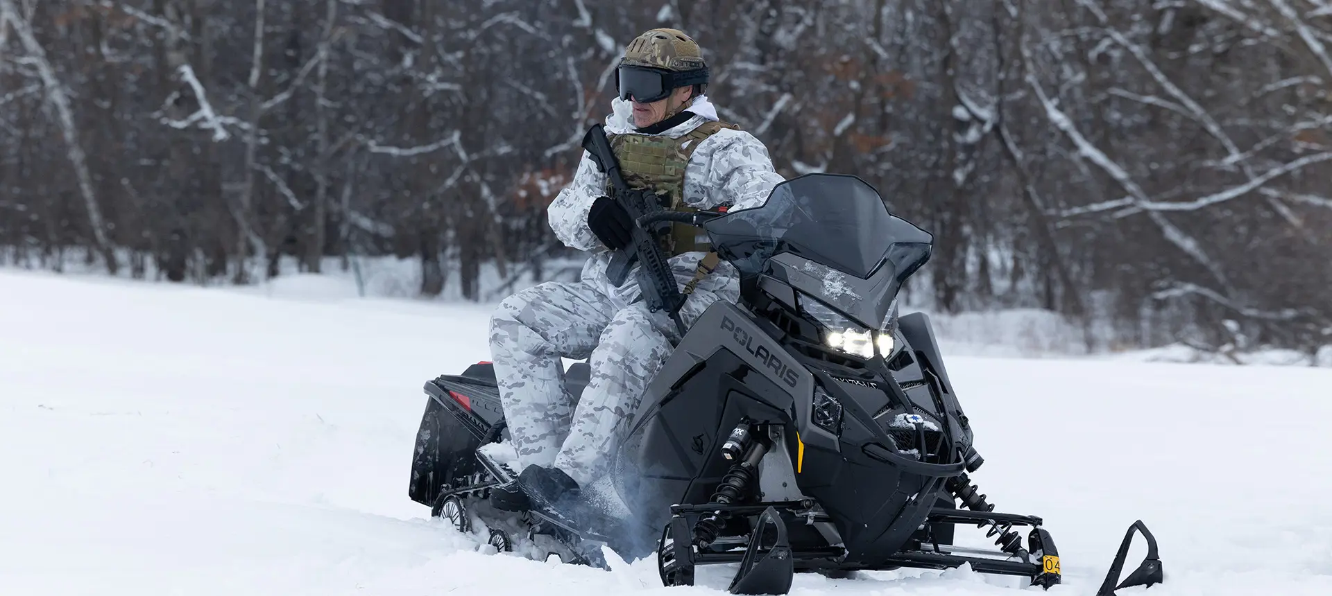 A soldier sitting on a Polaris Military snowmobile ready for action.
