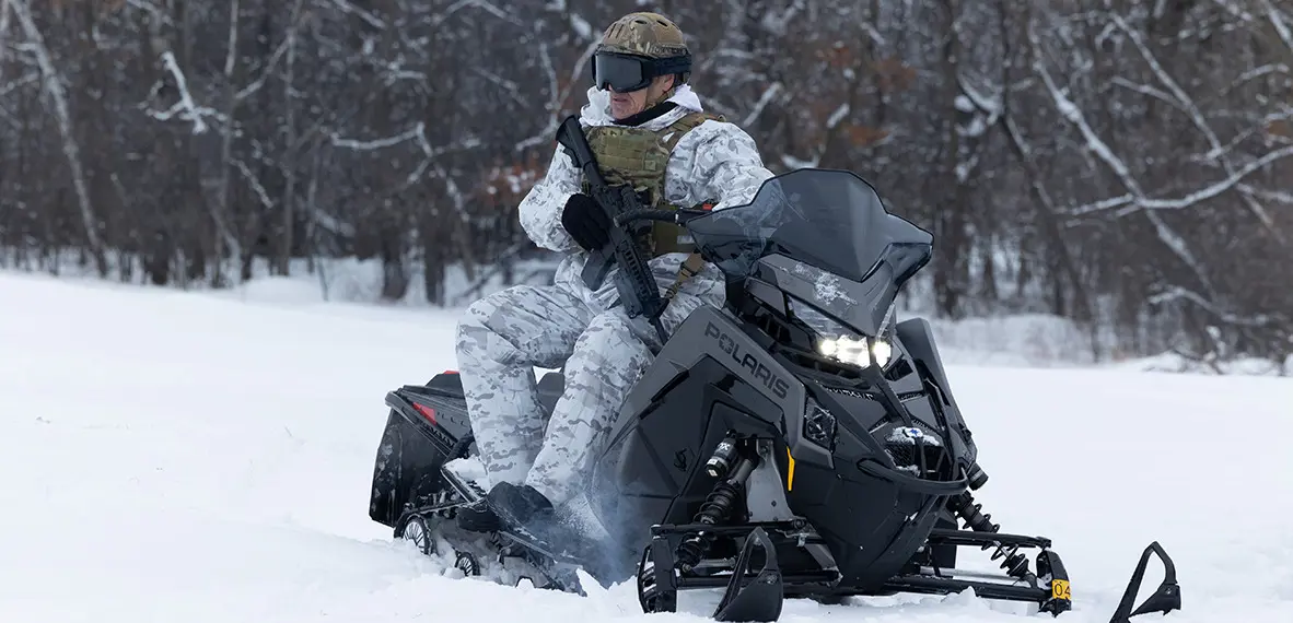 A soldier sitting on a Polaris Military snowmobile ready for action.